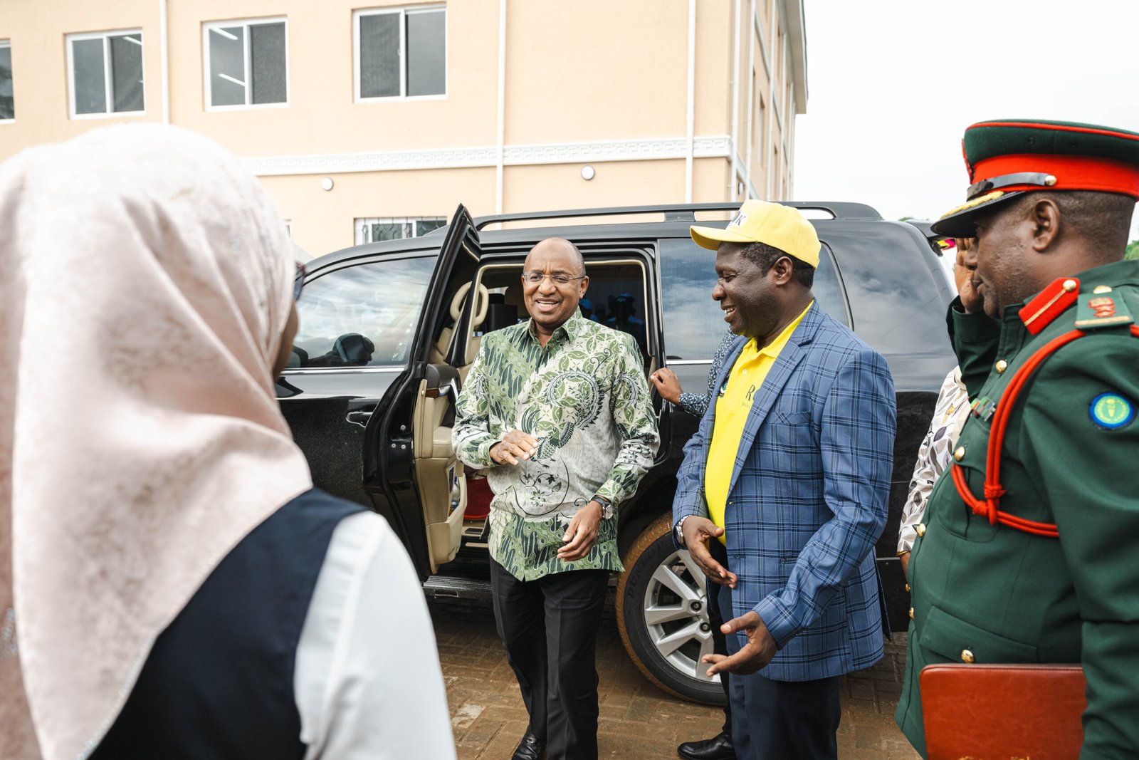President Hussein Mwinyi arriving at an official event in Zanzibar surrounded by local officials and security personnel.
