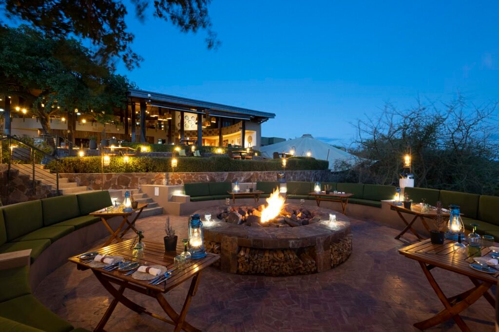 Luxury outdoor dining and fire pit area at Melia Serengeti lodge photographed at blue hour in Tanzania.