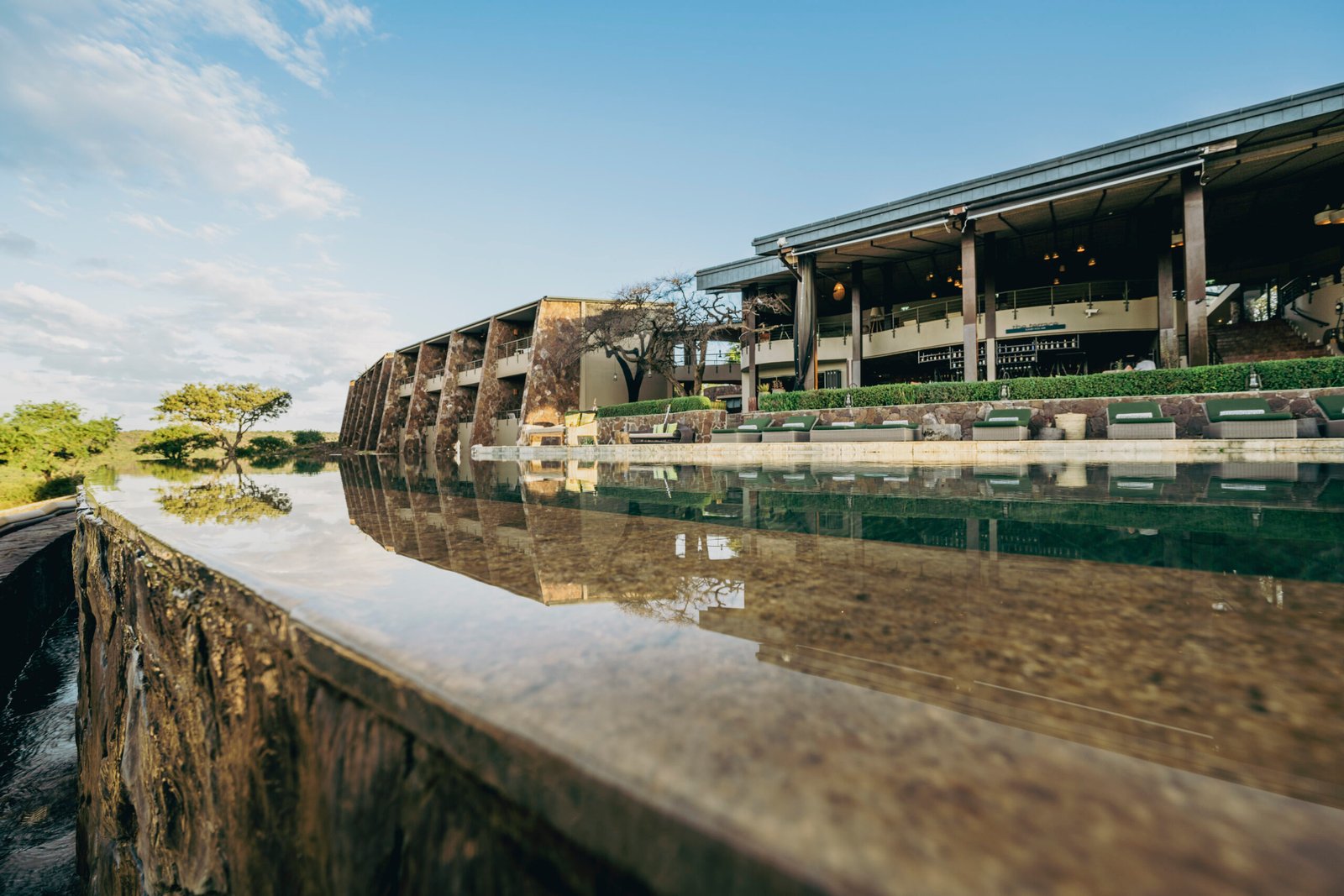 Infinity pool and luxury lodge exterior at Melia Serengeti Lodge photographed in Tanzania during golden hour.